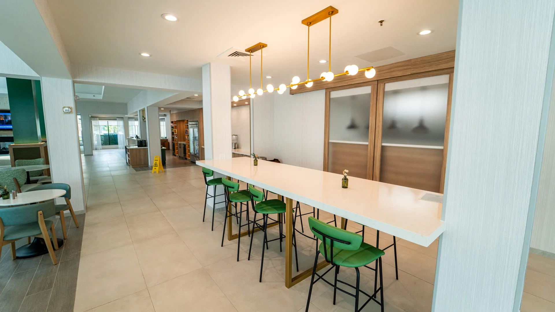 Long dining counter with a white top and green stools in front of sliding doors with frosted panels