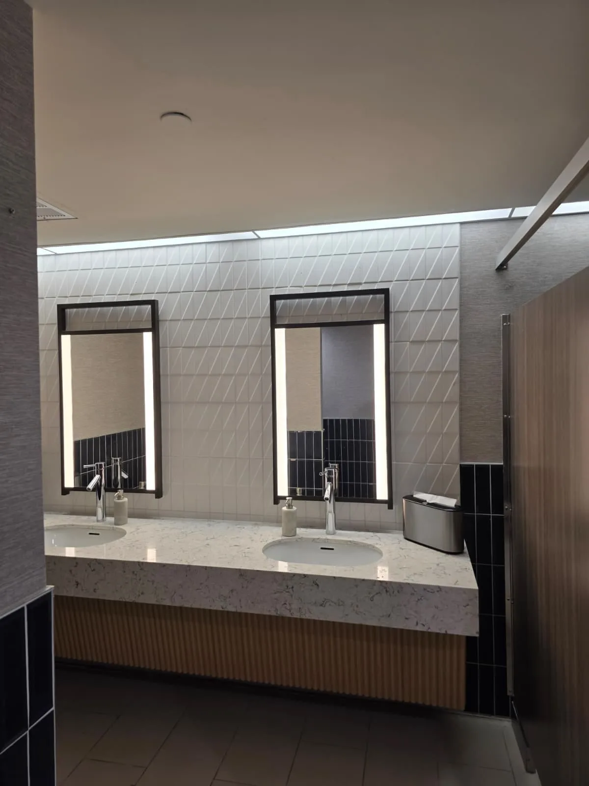 Double-sink restroom vanity with a light countertop, fluted cabinet front and two rectangular mirrors